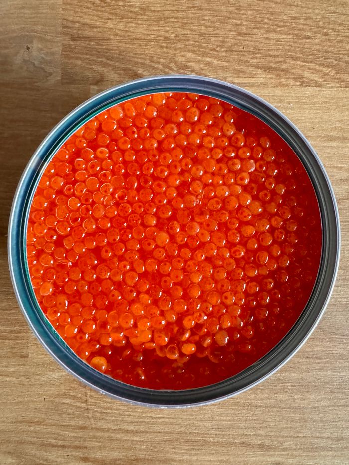 Vibrant red fish roe displayed in a tin can, perfect for gourmet cooking.